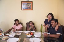 Família feliz sentada ao redor da mesa de jantar em casa . — Fotografia de Stock