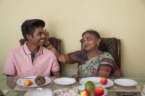 Grand-mère bénissant son petit-fils sur la table à manger à la maison . — Photo de stock