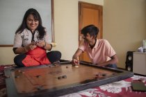 Son playing carrom-board with his mother at home. — Stock Photo
