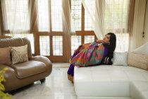 Mulher sentada confortavelmente em sua casa vestindo um terno indiano . — Fotografia de Stock