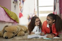 Giovane ragazza che aiuta sua sorella con i suoi studi in camera da letto a casa . — Foto stock