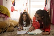 Young girl helping her sister with her studies at home. — Stock Photo