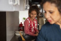 Young girl spending time with her mother in the kitchen at home. — Stock Photo