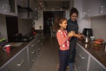 Jeune fille partageant un rire avec sa mère dans la cuisine . — Photo de stock