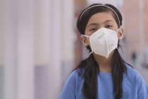 Jovencita parada afuera usando una máscara de contaminación . - foto de stock