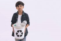 Giovane ragazzo in possesso di un cestino di riciclaggio con bottiglie di plastica . — Foto stock