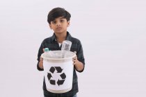 Jeune garçon tenant une poubelle de recyclage avec des bouteilles en plastique . — Photo de stock