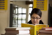 Mädchen liest ein Buch in einer Schulbibliothek — Stockfoto