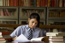 Menina estudando em uma biblioteca da escola — Fotografia de Stock