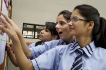 Gli studenti che guardano i risultati degli esami su una bacheca — Foto stock
