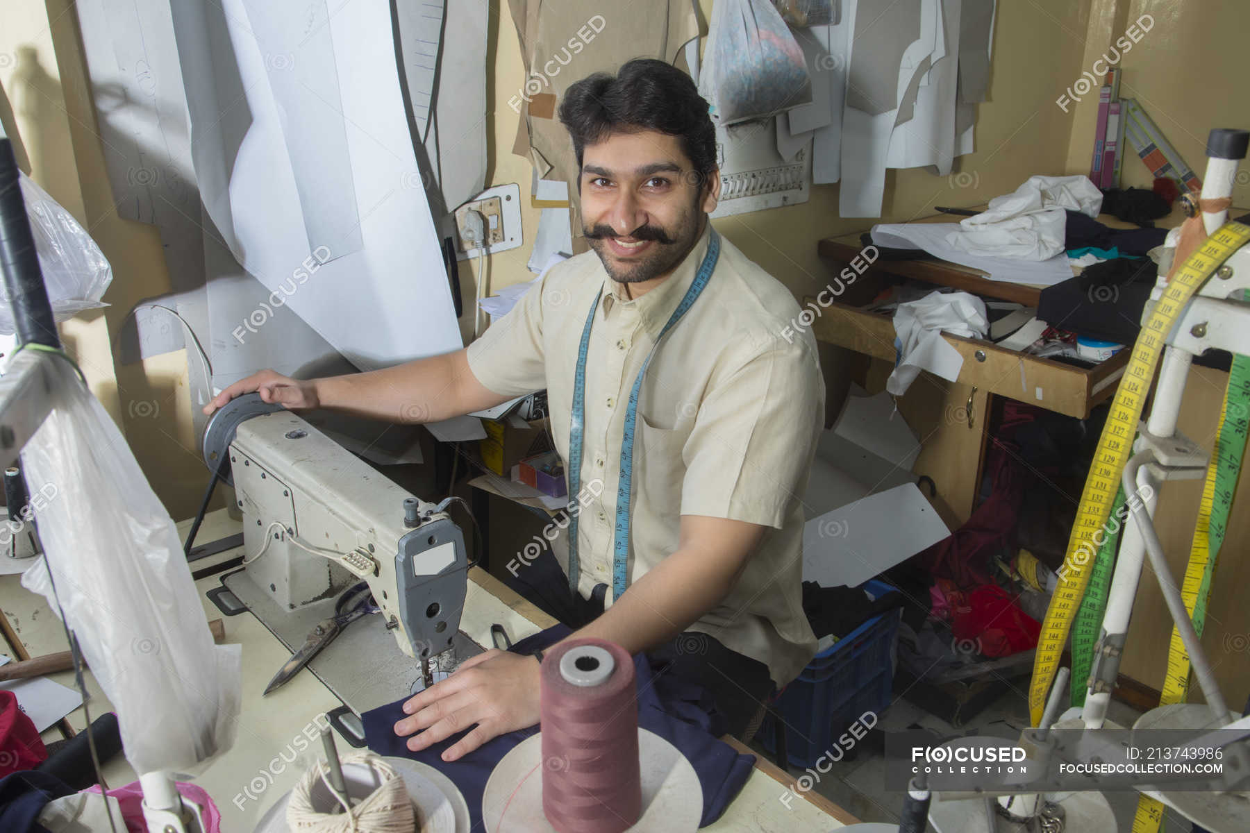 Male tailor working on sewing machine in with tailoring