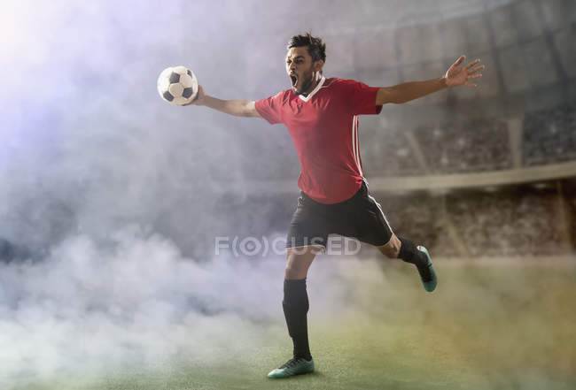 Footballer celebrating goal, running across the football field in the smoke — Stock Photo