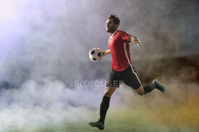 Футболист празднует гол, бежит по футбольному полю в дыму — стоковое фото
