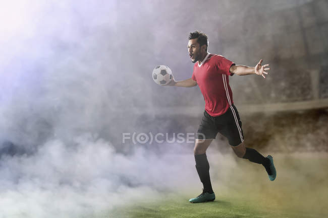 Футболист празднует гол, бежит по футбольному полю в дыму — стоковое фото