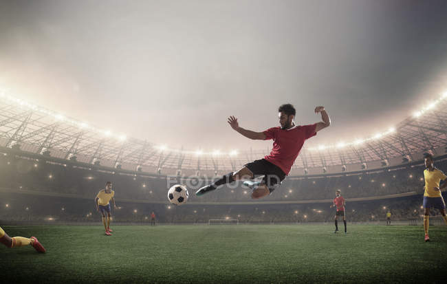 Un footballeur donne un coup de pied devant les projecteurs — Photo de stock