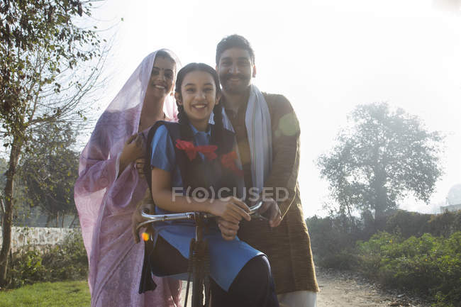 Família rural feliz com bicicleta na rua da aldeia — Fotografia de Stock