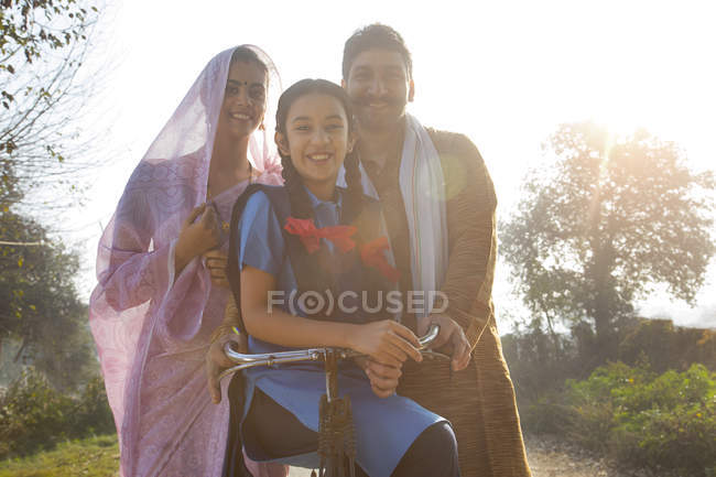 Счастливая сельская семья с велосипедом на деревенской улице — стоковое фото