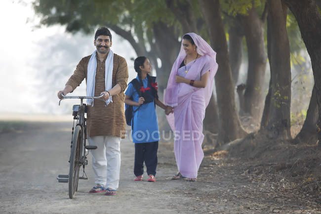 Felice coppia rurale con figlia a piedi sulla strada del villaggio — Foto stock