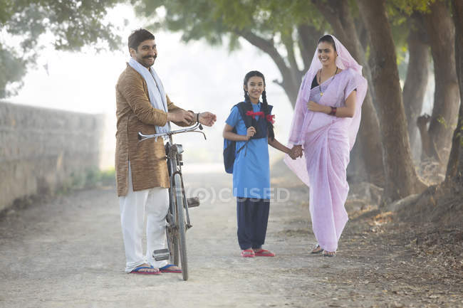 Happy rural couple with daughter walking on village street — Stock Photo