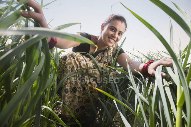 Visão de baixo ângulo do agricultor indiano fêmea em grama alta contra o céu azul — Fotografia de Stock