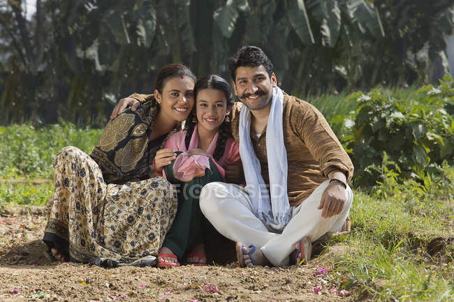 Smiling Indian family sitting on agriculture field — Stock Photo