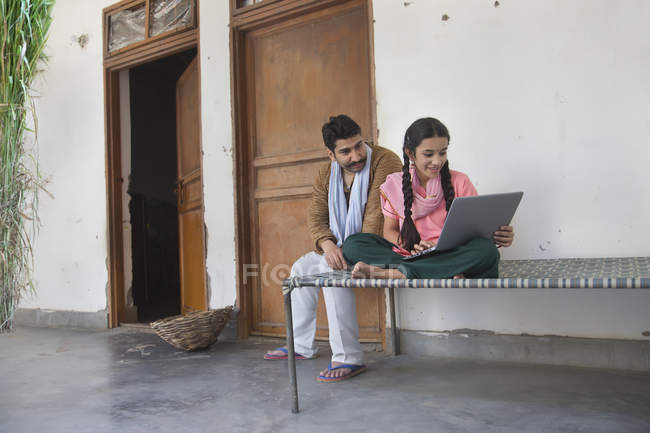 Дівчина сидить з батьком на ліжку і використовує ноутбук — стокове фото
