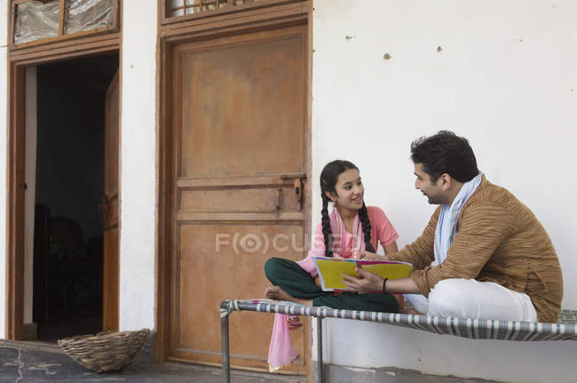 Дівчина сидить з батьком на ліжку і читає книгу — стокове фото