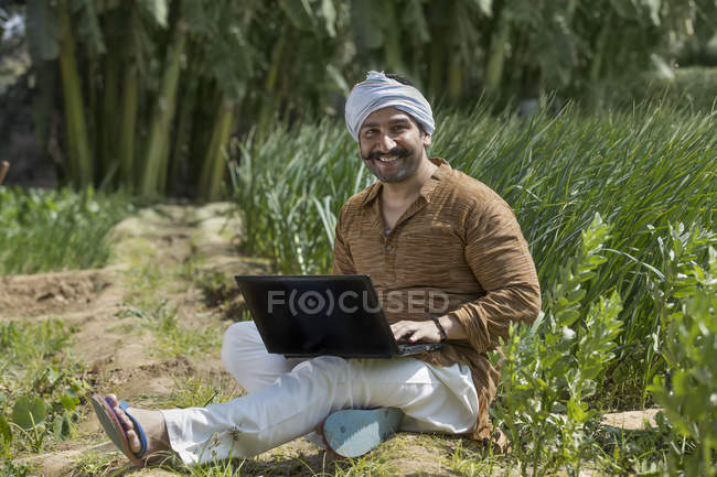 Agricultor indiano usando laptop usando computador no campo da agricultura — Fotografia de Stock