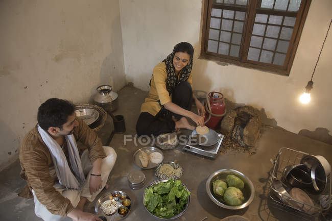 Индийская семья готовит еду на полу в помещении — стоковое фото