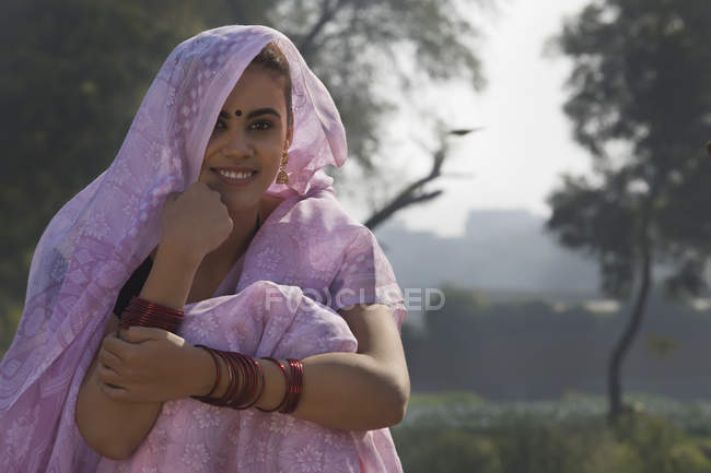 Frau im rosafarbenen Sari sitzt in der Nähe eines landwirtschaftlichen Feldes — Stockfoto