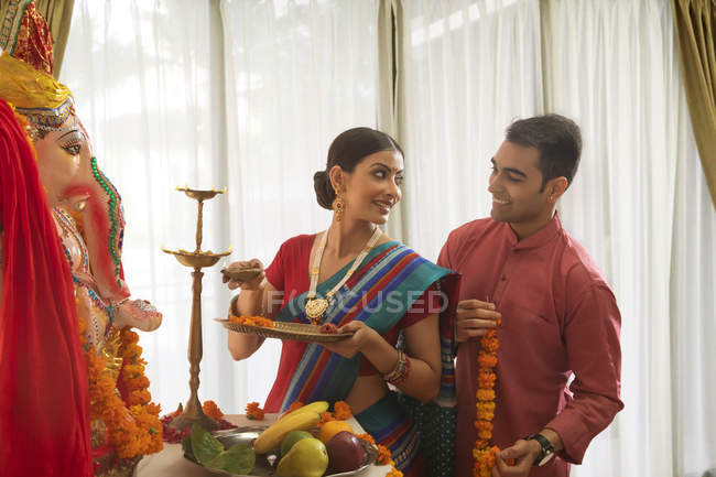 Indiano homem e mulher em roupas festivas perto estátua religiosa olhar uns para os outros — Fotografia de Stock