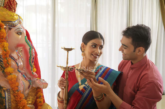 India hombre y mujer en ropa festiva cerca de estatua religiosa se miran entre sí - foto de stock