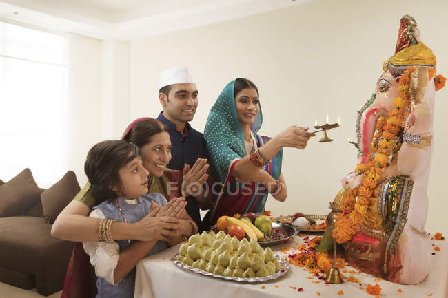 Familia india en ropa festiva celebrando ganesh chaturthi en interiores - foto de stock