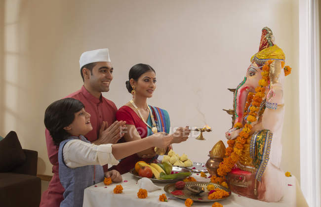 Famille en vêtements de fête effectuant aarti sur Ganesh chaturthi — Photo de stock