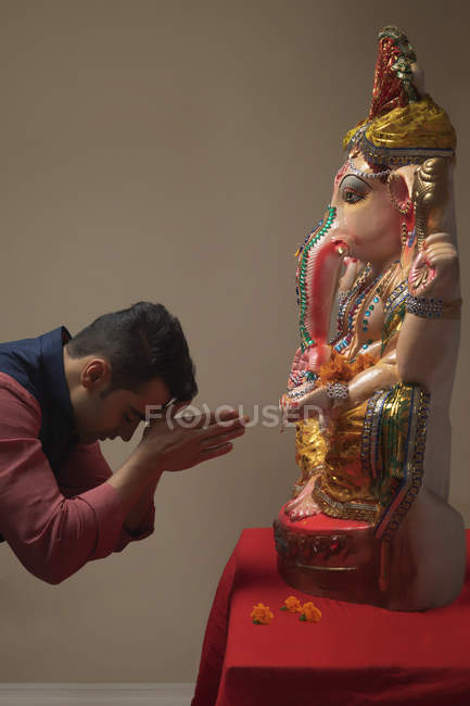 Женщина молится с поднятыми руками и закрытыми глазами перед идолом Ганпати — стоковое фото
