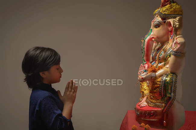 Mulher rezando com as mãos unidas e os olhos fechados na frente de Ganpati Idol — Fotografia de Stock