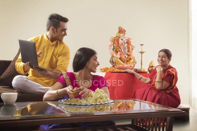 Indian young adult couple looking on old woman near religious Idol — Stock Photo