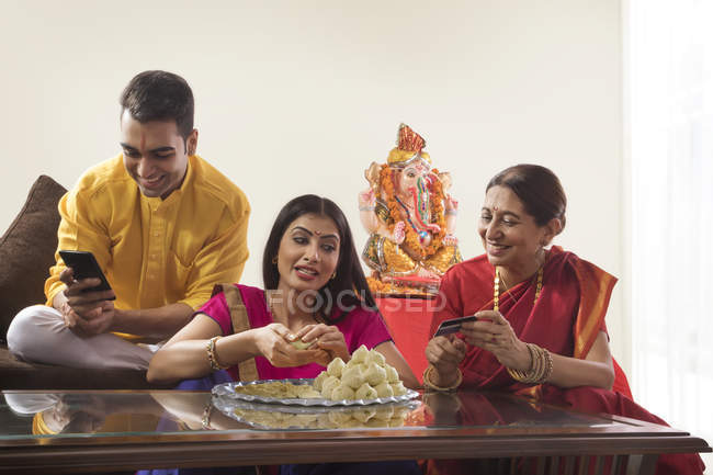 Indian young adult couple looking on old woman near religious Idol — Stock Photo