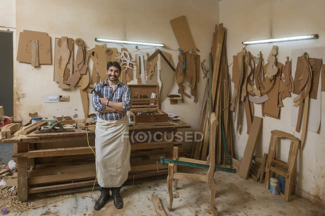 Ritratto di falegname in piedi nella sua bottega con un martello con le braccia incrociate — Foto stock