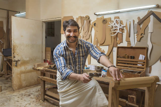 Улыбающийся плотник, работающий с молотком в мастерской — стоковое фото