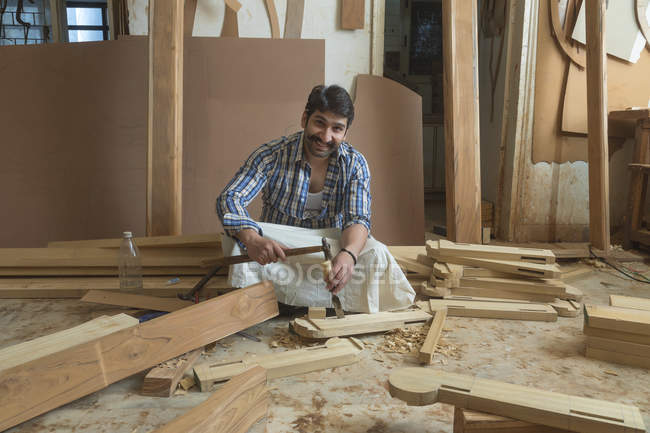 Плотник работает с зубилом и молотком на полу в мастерской — стоковое фото