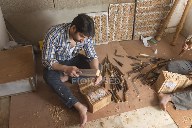 Falegname realizzando sculture e disegni su legno utilizzando scalpello in officina — Foto stock