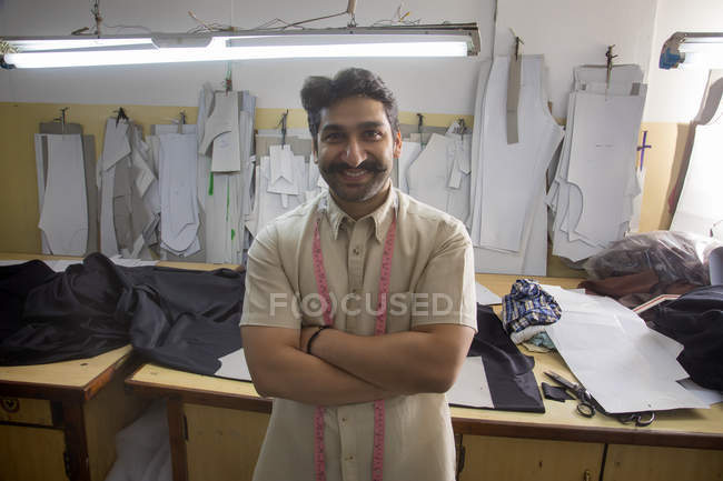 Smiling tailor standing with arms crossed in workshop — Stock Photo