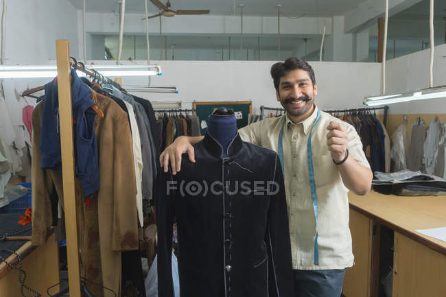 Tailor standing beside mannequin wearing semi-stitched coat in workshop — Stock Photo