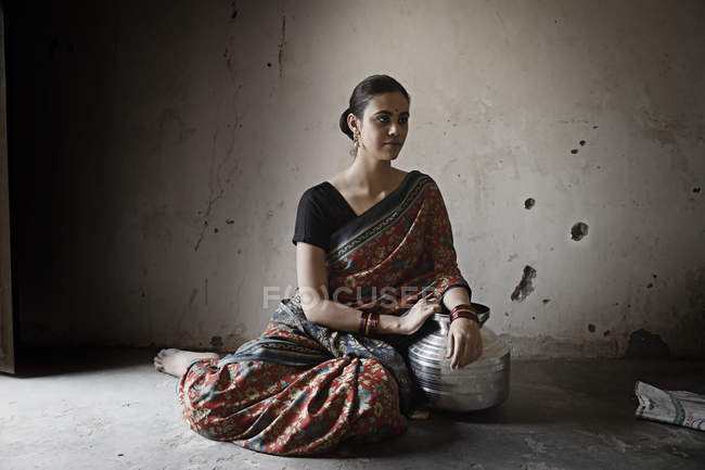 Индийская женщина, сидящая на полу в комнате с тусклым освещением — стоковое фото