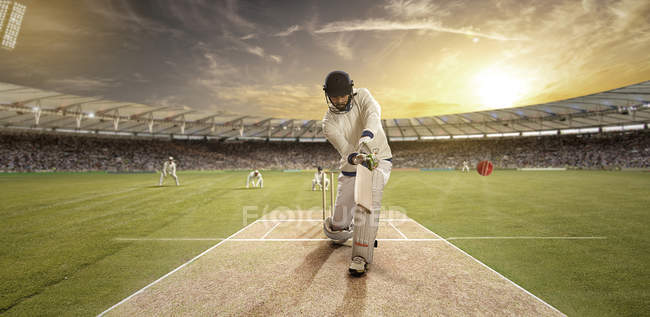 Jovem desportista bola impressionante enquanto rebatendo no campo de críquete — Fotografia de Stock