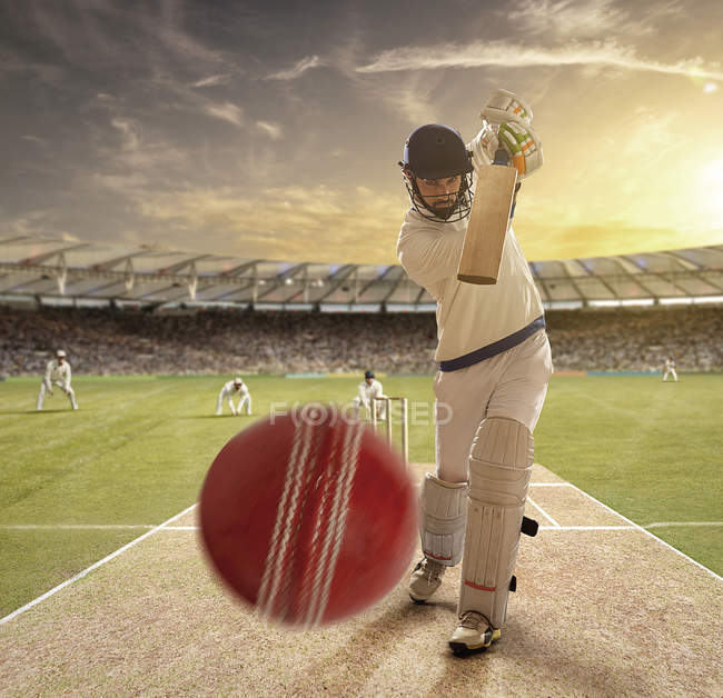 Joven deportista golpeando pelota mientras batea en el campo de cricket, enfoque selectivo - foto de stock