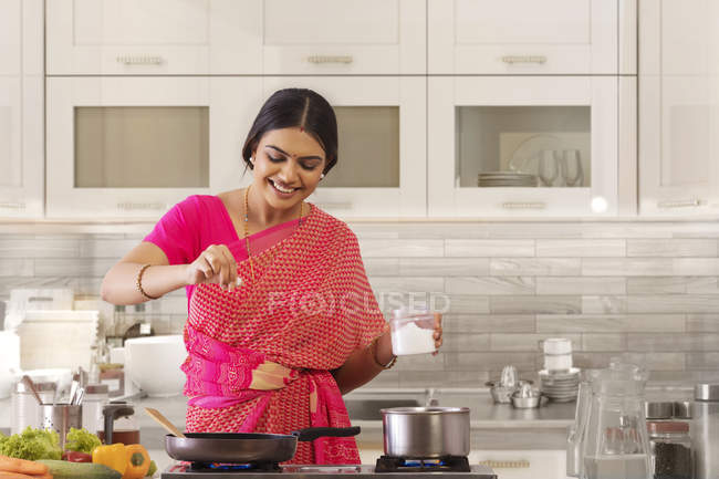 Женщина посыпает соль в блюдо — стоковое фото