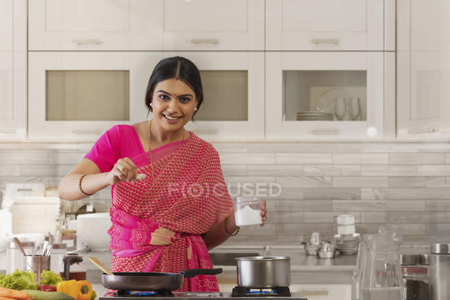 Woman sprinkling salt in the dish — Stock Photo