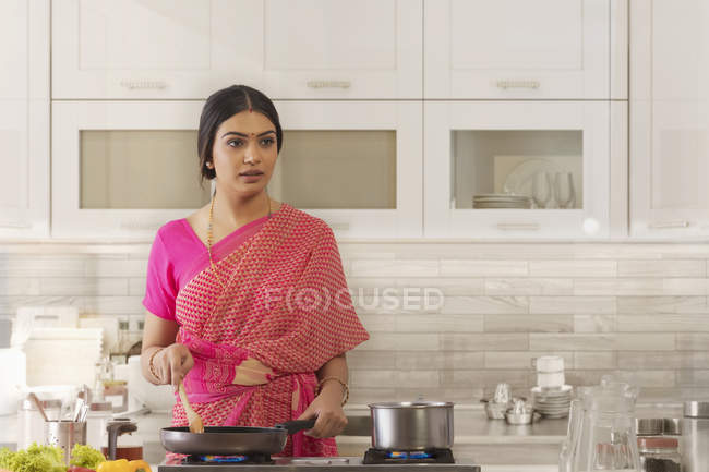 Mujer en saree cocinar en la cocina - foto de stock